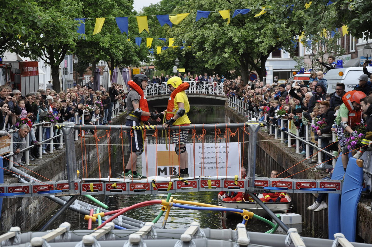 Zwei Studierende stehen auf ihrer selbstgebauten Brücke über dem Fleth